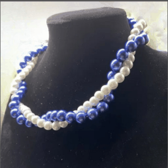 Elegant twisted royal blue and white glass pearl necklace on display.