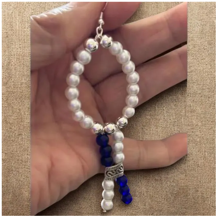 Peace N Beads White Oval Drop Earrings with white and blue beads and silver accents held in hand