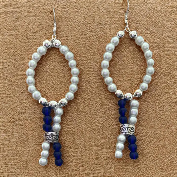 Peace N Beads white oval drop earrings with blue and silver decorative beads on beige background