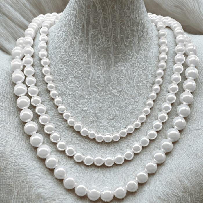 Classic Single Strand White Pearl Necklace with silver toggle clasp displayed on textured surface.