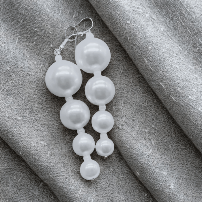 Pearl Perfection White Glass Drop Earrings with handcrafted white glass pearls on a silver hook against gray fabric background