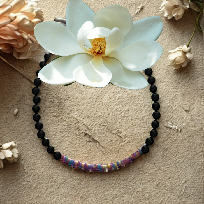 Rainbow Hematite and Black Onyx Protection Bracelet by Peace N Beads displayed with white flower on textured background