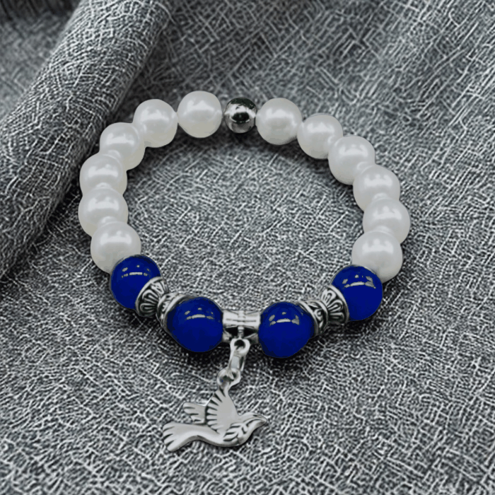 Blue Jade and White Glass Pearl Charm Bracelet with Bird Pendant on Fabric Background
