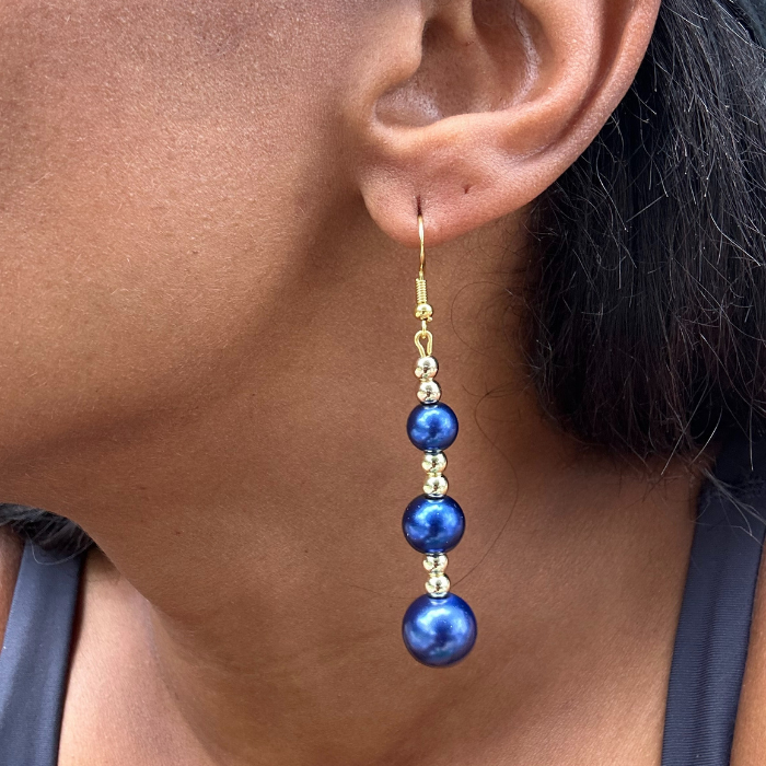 Close-up of an ear wearing a blue and gold beaded earring.