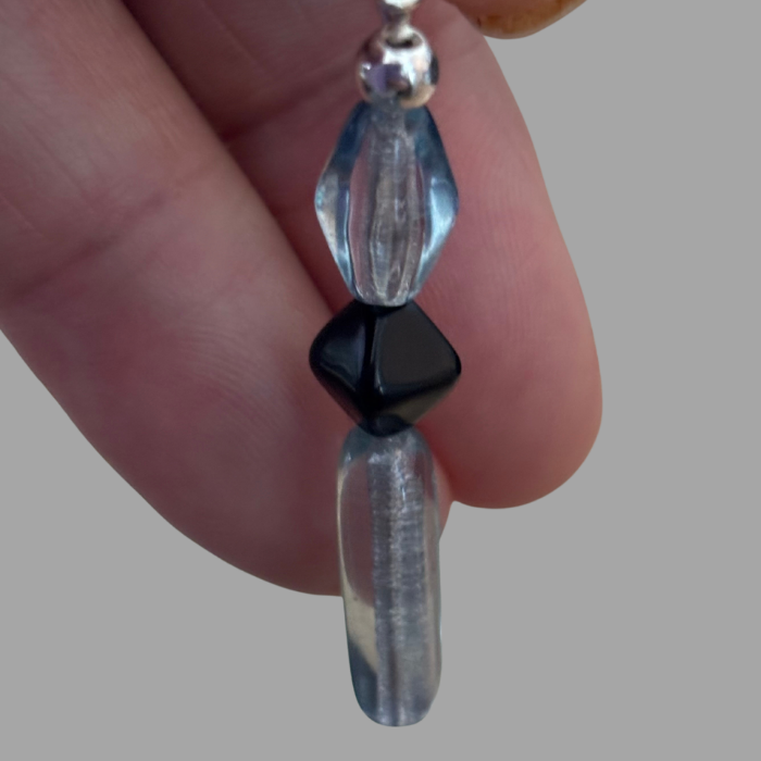 Peace N Beads Design Blue and Black Crystal Bead Earrings held between fingers with clear and black beads