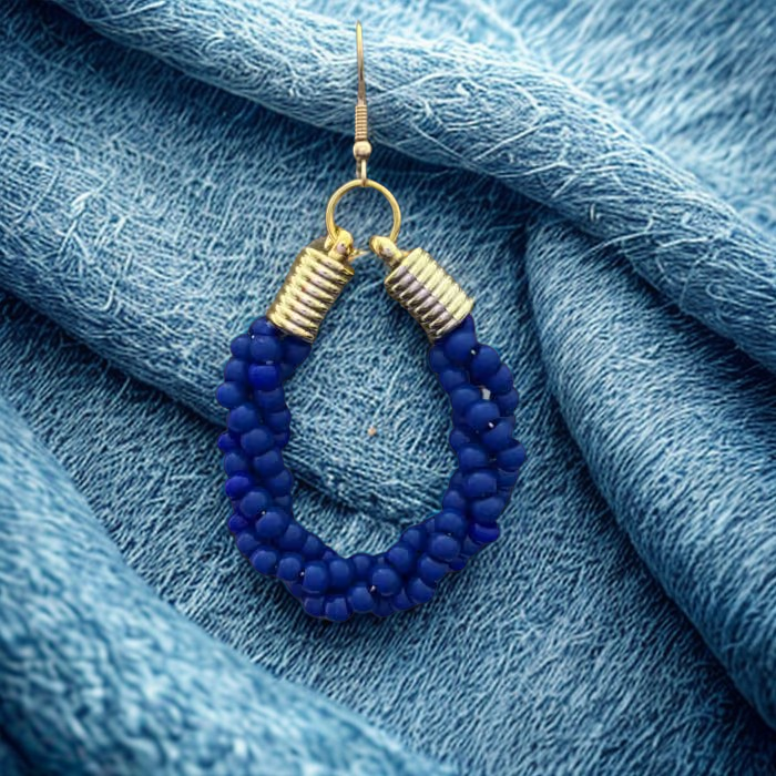 Gold Accented Twisted Royal Blue and Gold Hoop Earrings by Peace N Beads on textured blue fabric