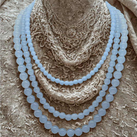 Handmade blue glass bead necklace from Peace N Beads displayed on textured fabric background