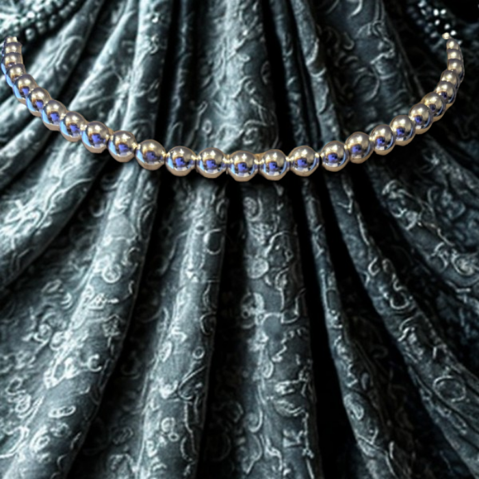 The Connection of Silver Hematite Necklace by Peace N Beads Design displayed on patterned fabric background