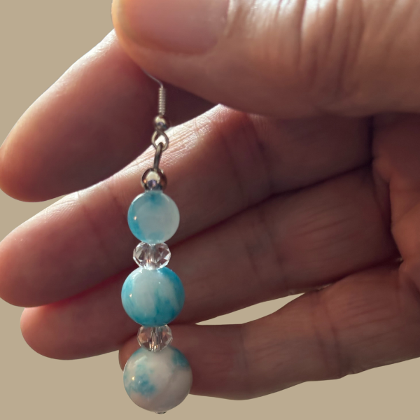 Hand holding Three-Tiered Blue and White Crystal Earrings from Peace N Beads Design with marbled beads and clear spacer crystals