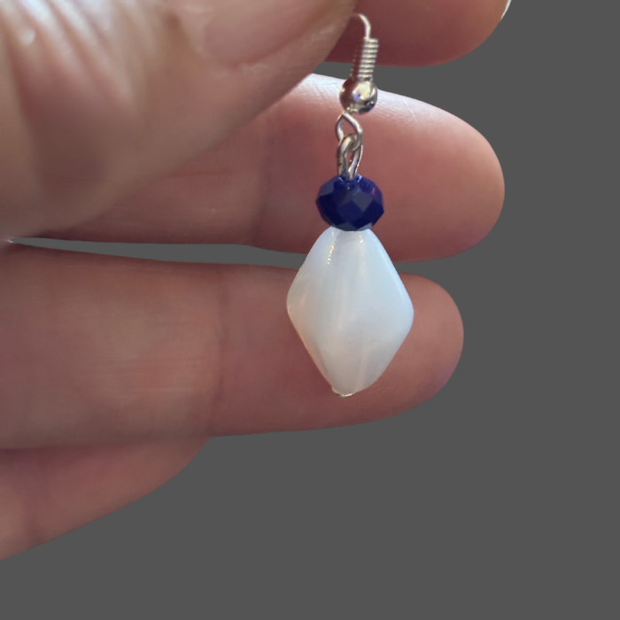 White Acrylic Blue Crystal Drop Earrings held by hand showing detailed blue crystal and white acrylic design