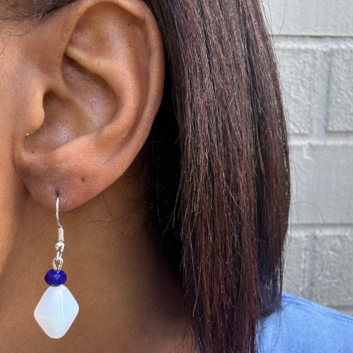 White Acrylic Blue Crystal Drop Earrings by Peace N Beads Design worn on ear with blue shirt background