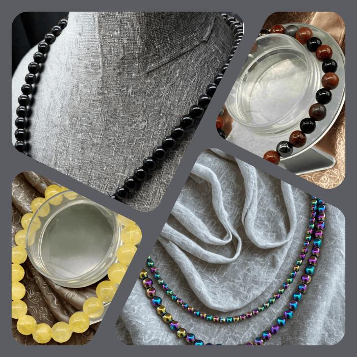 Genuine Gemstones Jewelry Collection featuring handcrafted beaded necklaces in black and reddish brown stones displayed on clear stands and busts