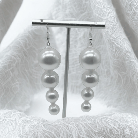 Pearl Perfection White Glass Drop Earrings with four graduated pearl beads in a drop design on silver hooks against a white lace background