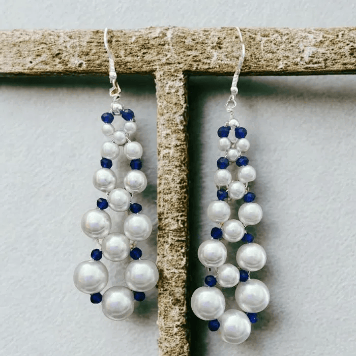 4 Inch Drop White Glass Pearl and Blue Crystal Earrings beautifully arranged on a rustic display
