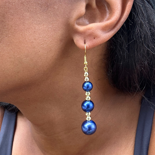 Close-up of an ear wearing a blue and gold beaded earring.