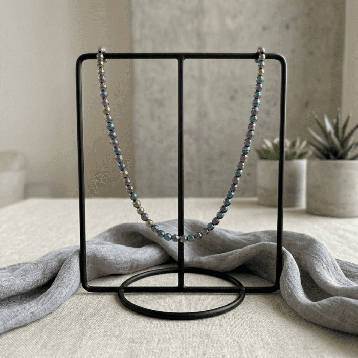 Bohemian Dream Rainbow Hematite Necklace displayed on a modern black jewelry stand