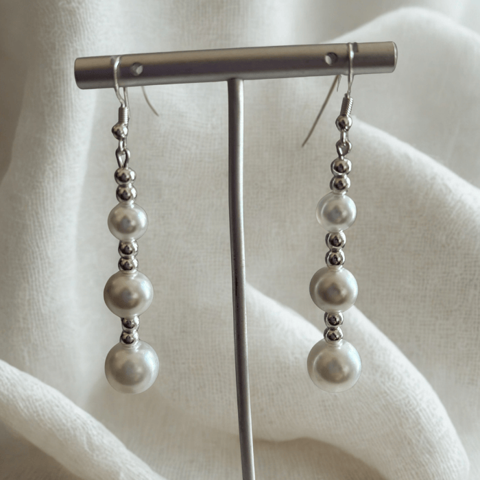 Elegant Hematite and Glass Pearl Drop Earrings on a display stand against a soft background