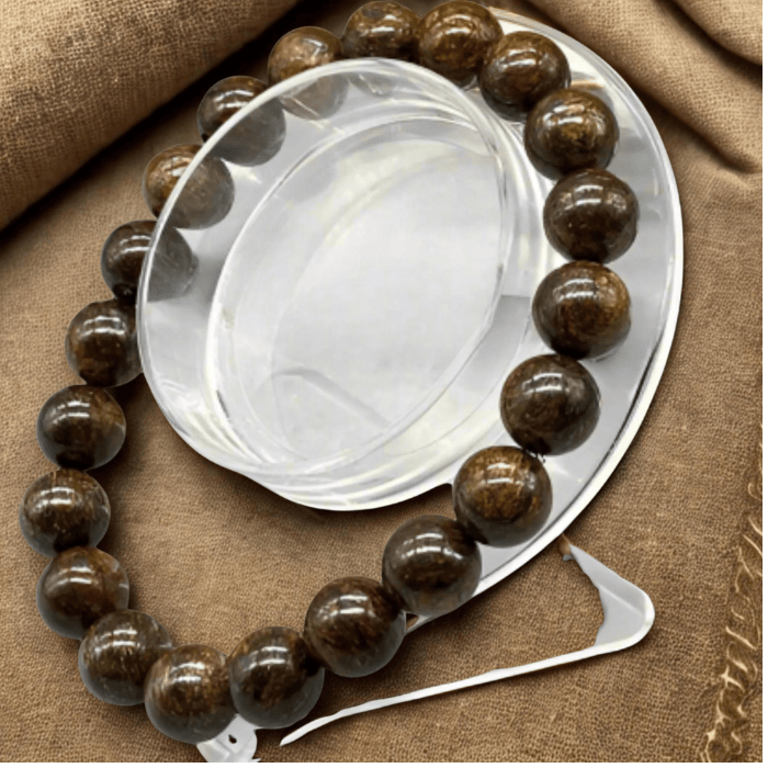 Genuine Brown Bronzite Gemstone Bracelet displayed on a round plate with a textured background