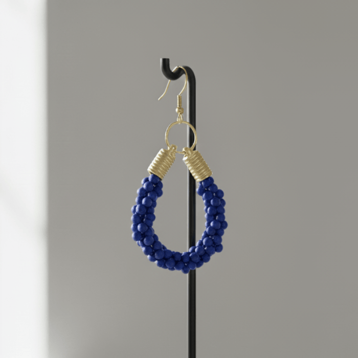 Gold Accented Twisted Royal Blue and Gold Hoop Earrings displayed on a stand