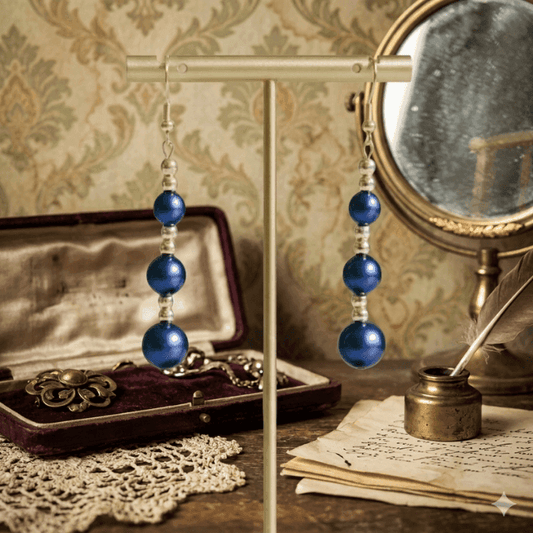 Hematite and Blue Glass Pearl Drop Earrings displayed elegantly on a stand against a vintage backdrop