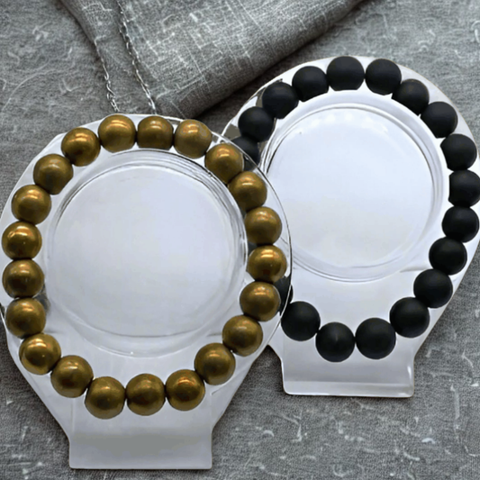 Dignified Double Protection Bracelets featuring gold and black beads on clear display stands