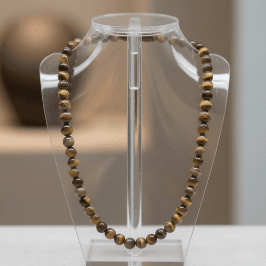 Feel Empowered with a Tiger Eye Necklace displayed on a clear stand for showcasing its natural beauty