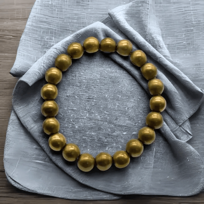 Genuine Golden Hematite Bracelet with Smooth, Reflective Beads on a Soft Grey Background