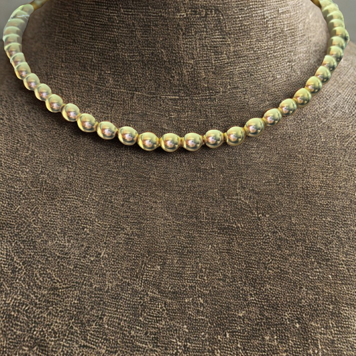 Gold Hematite Gemstone Necklace featuring shiny beads on a textured display stand