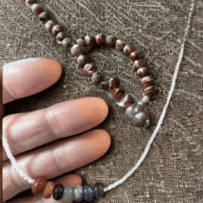 Handcrafted Chakra Necklace with Genuine Gemstones displayed on a textured background and held in a hand