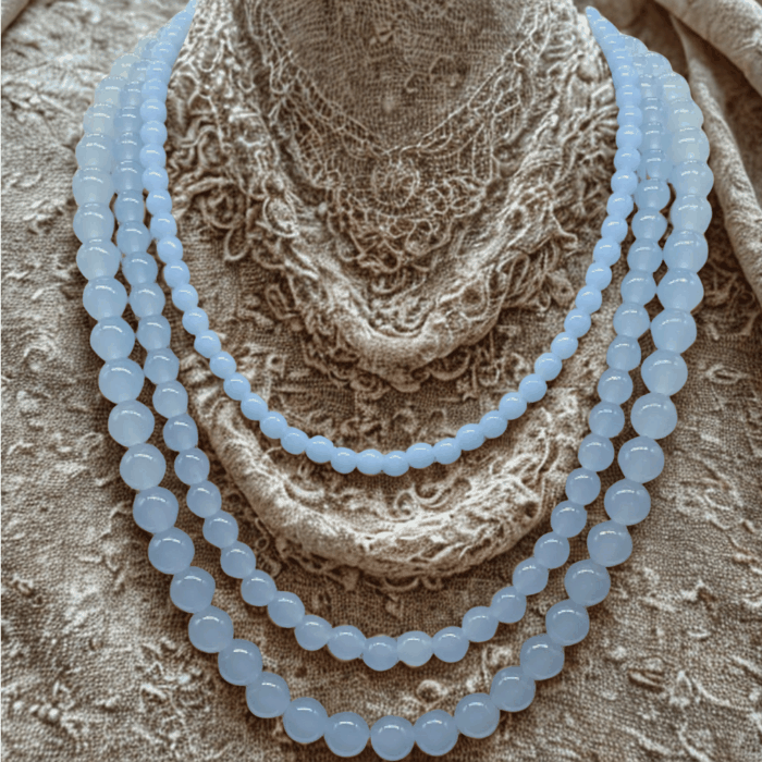 Handmade blue glass bead necklace from Peace N Beads displayed on textured fabric background