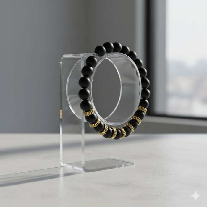 Luxurious Black and Gold Gemstone Bracelet displayed on a clear stand with sunlight in the background