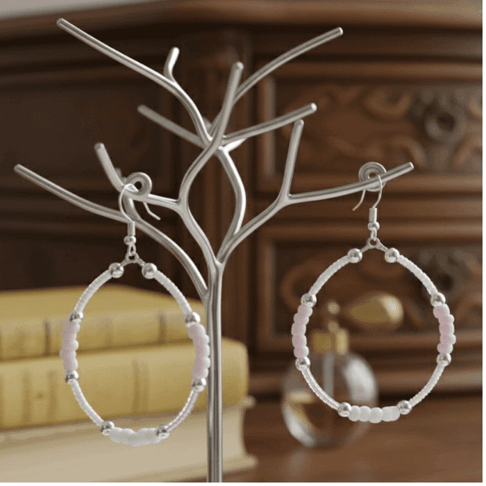 Pink Seed Bead Hoop Earrings displayed on a stylish jewelry stand against a wooden background