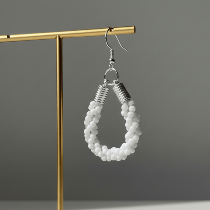 Twisted Royal Blue and White Hoop Earrings displayed elegantly on a gold earring stand