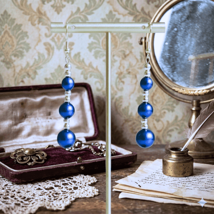 Hematite and Blue Glass Pearl Drop Earrings elegantly displayed on a stand with vintage decor