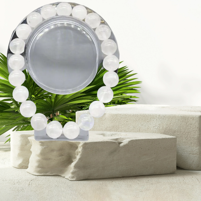 Peace N Beads White Jade Gemstone Bracelet displayed on a stone pedestal with a tropical background